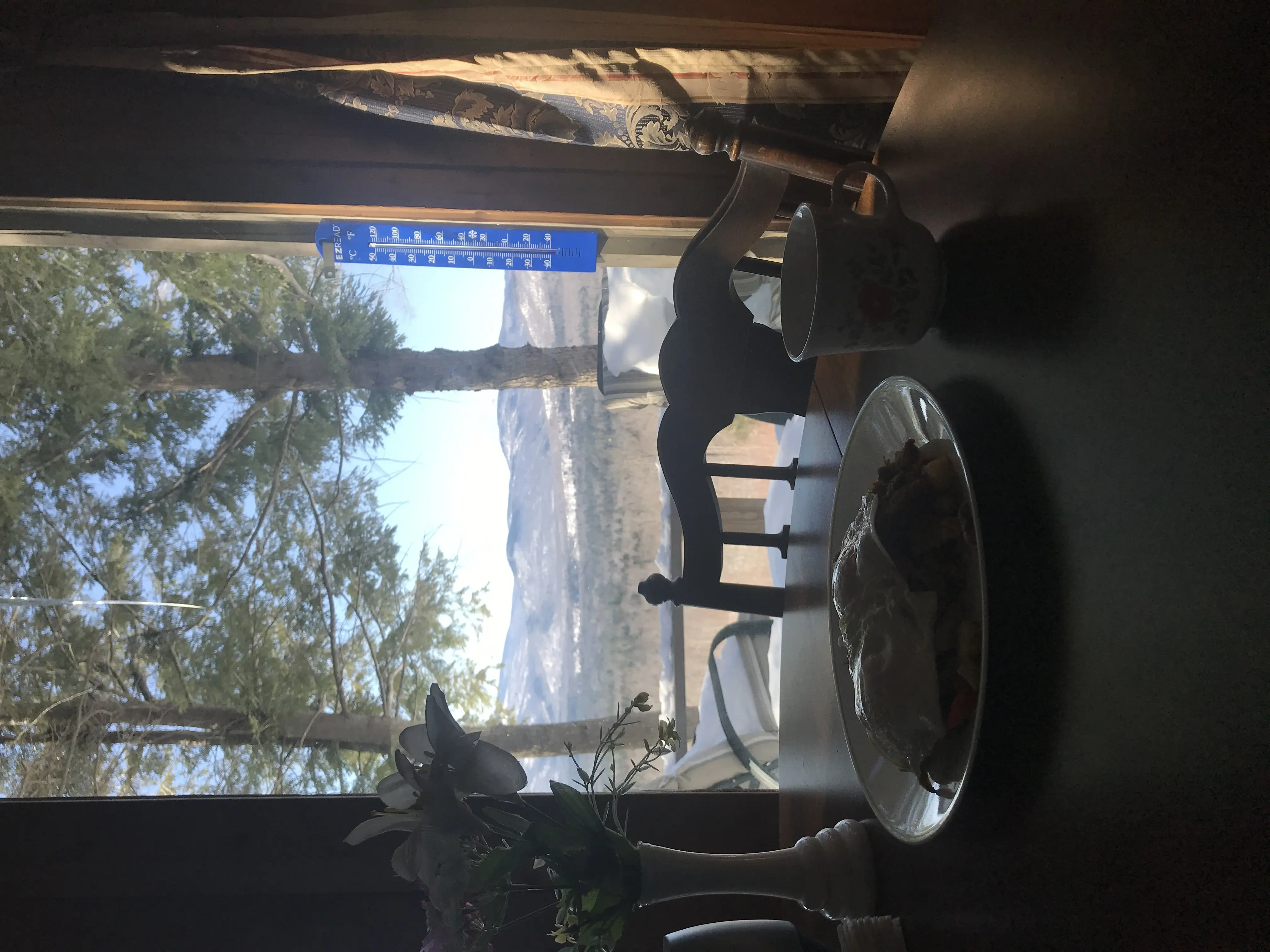 Breakfast on a table that looks out a window to a view of the mountains.