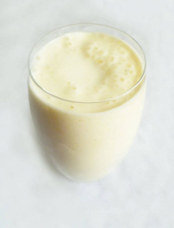 A short glass of creamy pineapple breakfast smoothie.