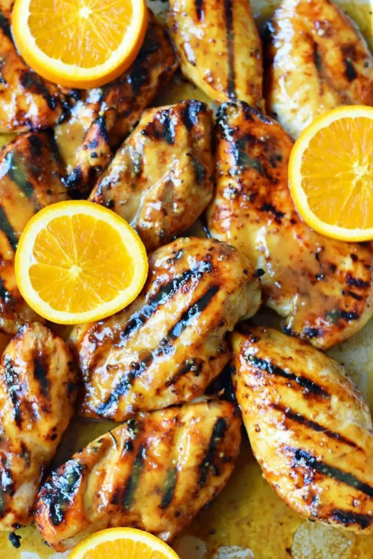 A plate of juicy honey mustard grilled chicken topped with orange slices.