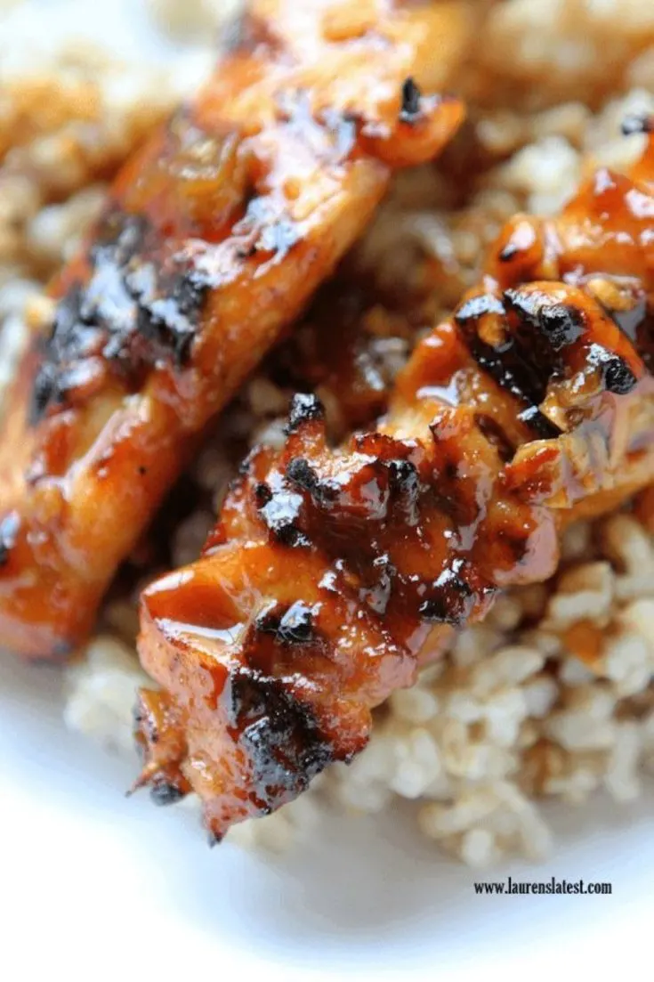 A bowl with rice and Asian sweet and spicy chicken skewers.