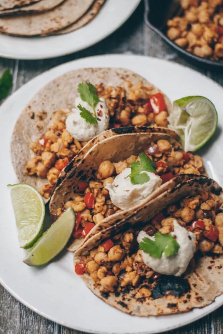 A plate of three chickpea tempeh tacos topped with cashew crema.