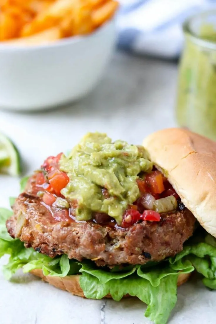 A large grilled chili lime turkey burger topped with salsa and guacamole.