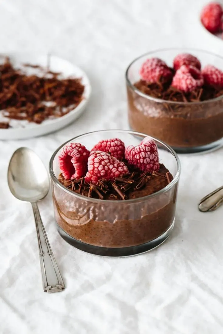 Two small dishes of chocolate chia pudding topped with raspberries.