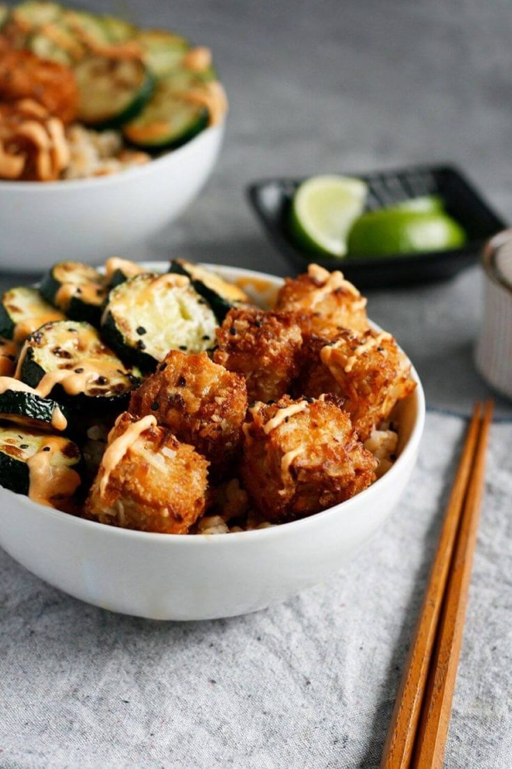 A bowl of coconut crusted tofu topped with sweet chili sauce.