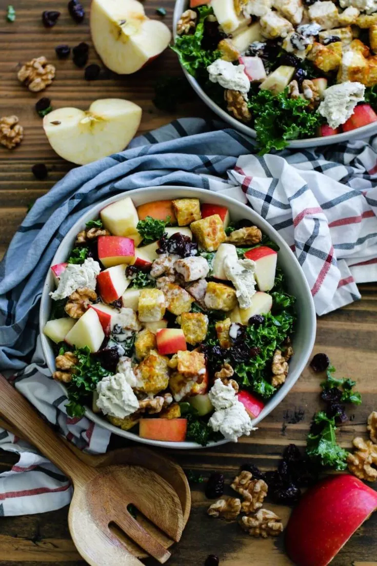 A large bowl of cranberry apple walnut kale salad with tempeh crumbles.