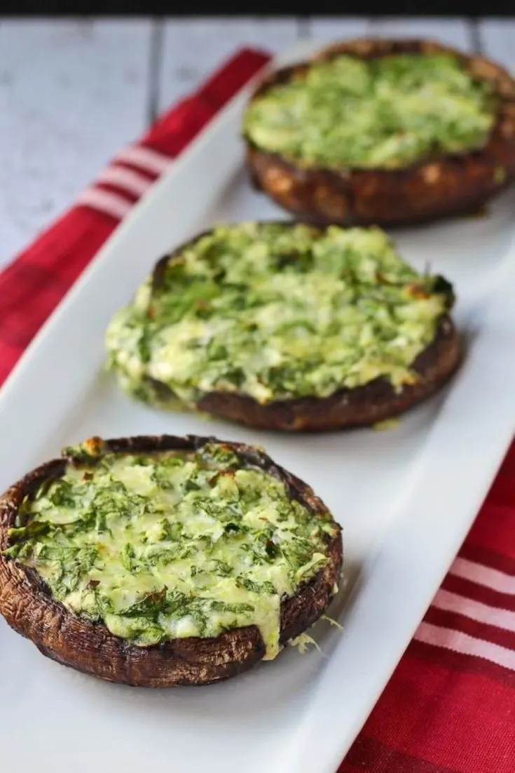 A plate with three grilled portobello mushrooms stuffed with spinach and cheese.