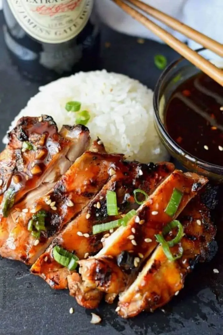 A plate of teriyaki chicken with rice and sauce.