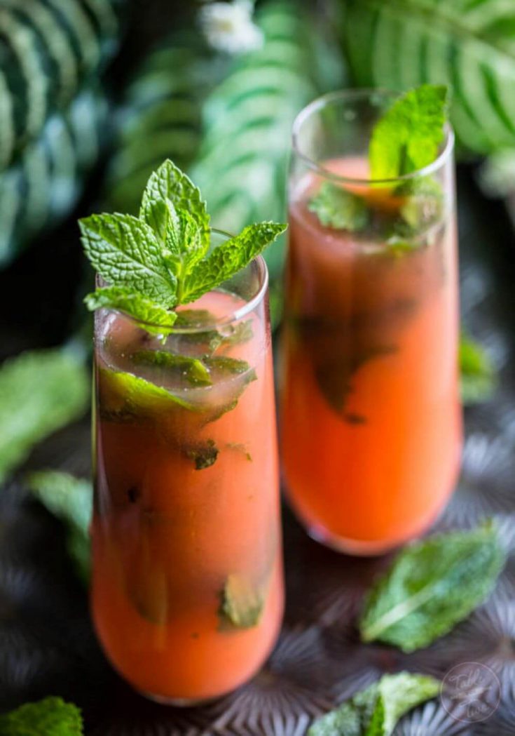 Two full glasses of guava mojito topped with mint.