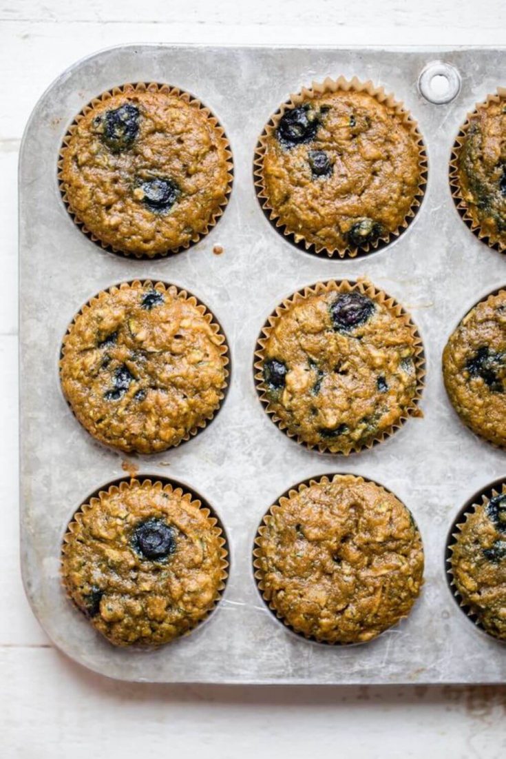 A muffin pan full of healthy blueberry zucchini muffins right out of the oven.