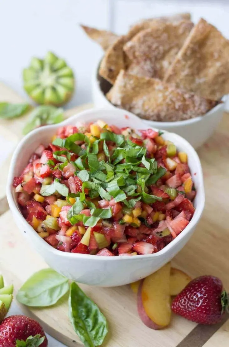 A bowl of healthy fruit salsa with another bowl of cinnamon sugar pita chips.