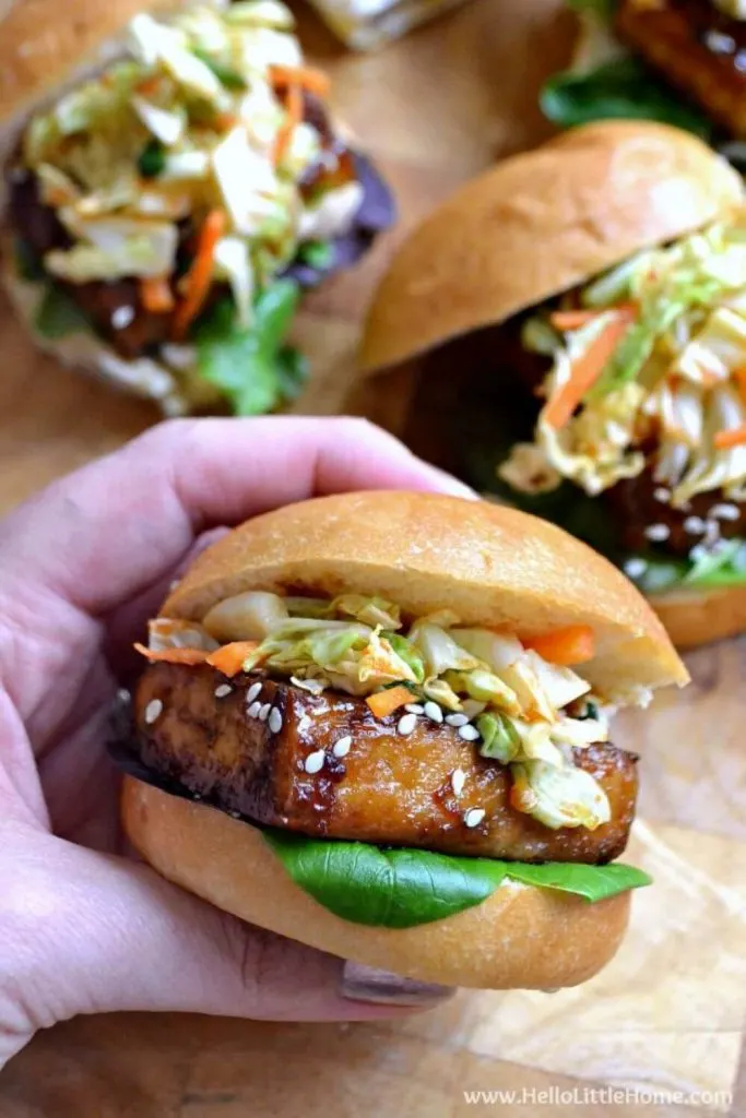 A hand holding a delicious Korean BBQ tofu slider topped with kimchi.