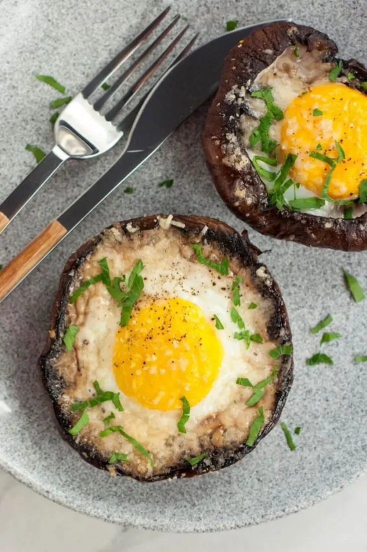 A plate of two portobello baked eggs topped with herbs.