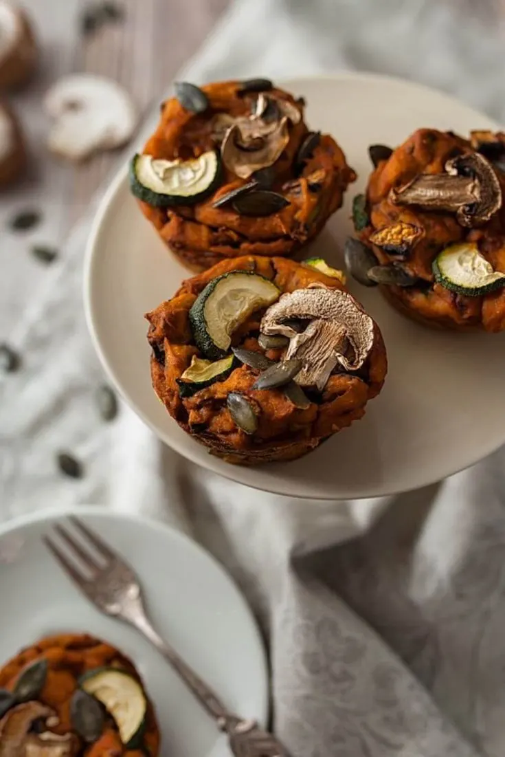 Several savory sweet potato muffins on a plate topped with mushrooms and zucchini.