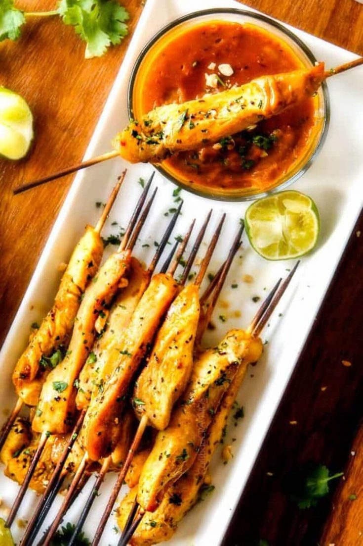 A plate of Thai chicken satay skewers with a dish of peanut sauce.