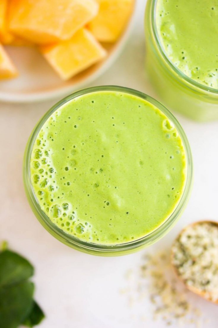 An overhead look at a healthy vegan breakfast green smoothie in a glass.
