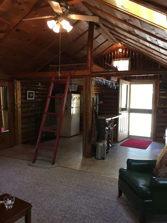 The inside of a cozy and romantic log cabin rental with a loft in Maine.