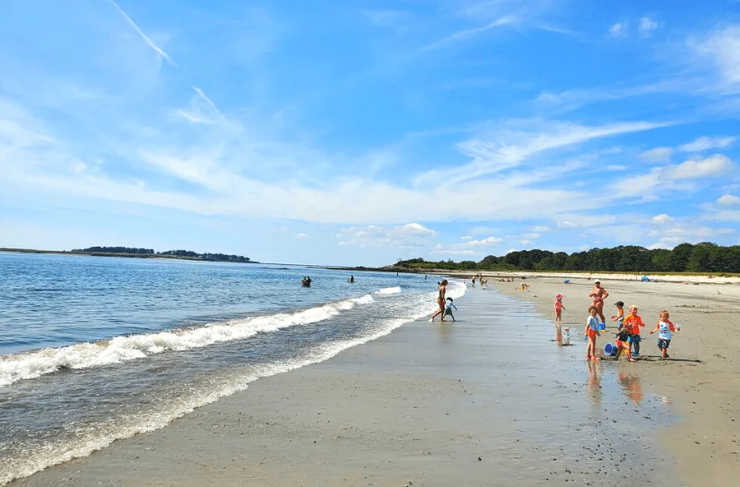 People playing on the beach and ocean in Crescent Beach State Park, a beach near Portland, Maine.